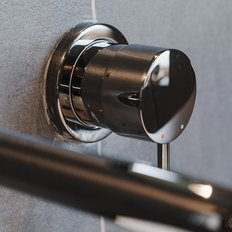 Ein eleganter, glänzender Wasserhahn mit einem modernen Design, montiert an einer grauen Wand, strahlt zeitgenössischen Stil aus.