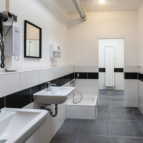Ein modernes Badezimmer mit zwei Waschbecken, einem großen Spiegel und einem Handtuchspender an der Wand.
