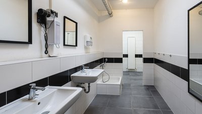 Ein modernes Badezimmer mit zwei Waschbecken, einem großen Spiegel und einem Handtuchspender an der Wand.
