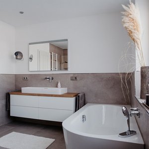 Ein modernes Badezimmer mit einer eleganten Badewanne und einem stilvollen Waschbecken auf einem Holzregal.