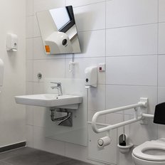 Ein modernes barrierefreies Badezimmer mit einem Toilettenstuhl und Haltegriffen für zusätzliche Unterstützung.